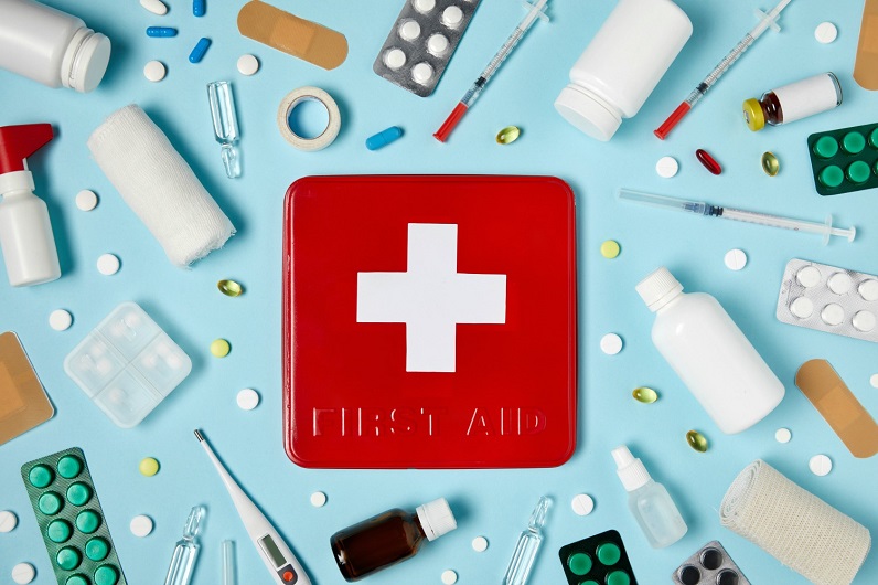 picture of a first aid kit essential content spilled on a blue background 