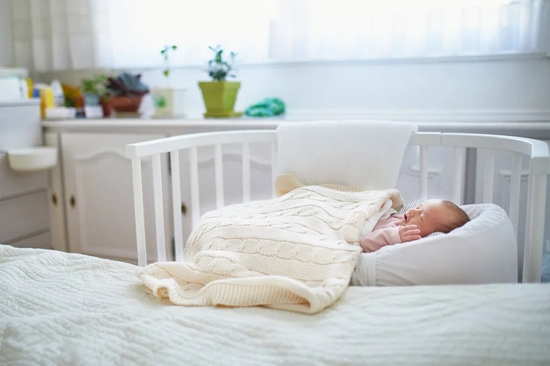 picture of a baby sleeping in a white crib beside a big bed in the bedroom